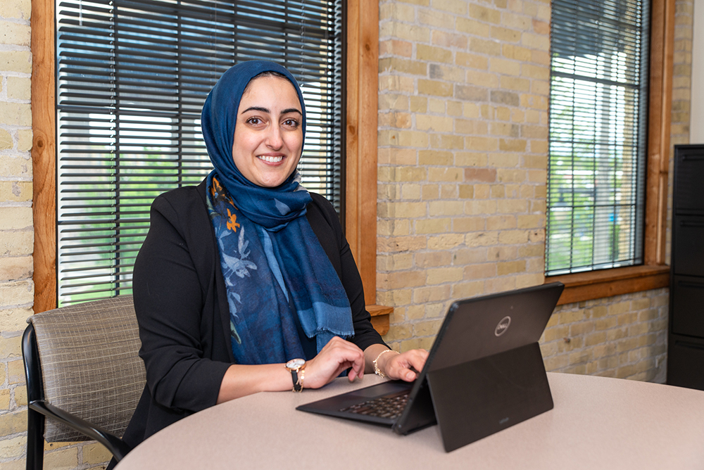 Dalia Saleh smiling and working at a table on a tablet.