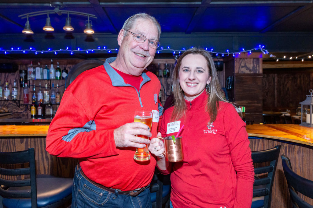 John Johnson and Jenny Tempelis holding drinks in front of the bar