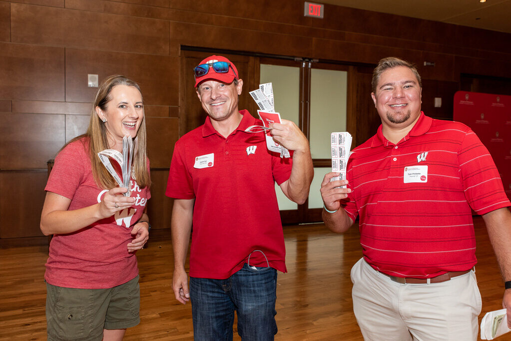 Jason Lau, Tyler Prickette, and Jenny Tempelis smile with raffle tickets.