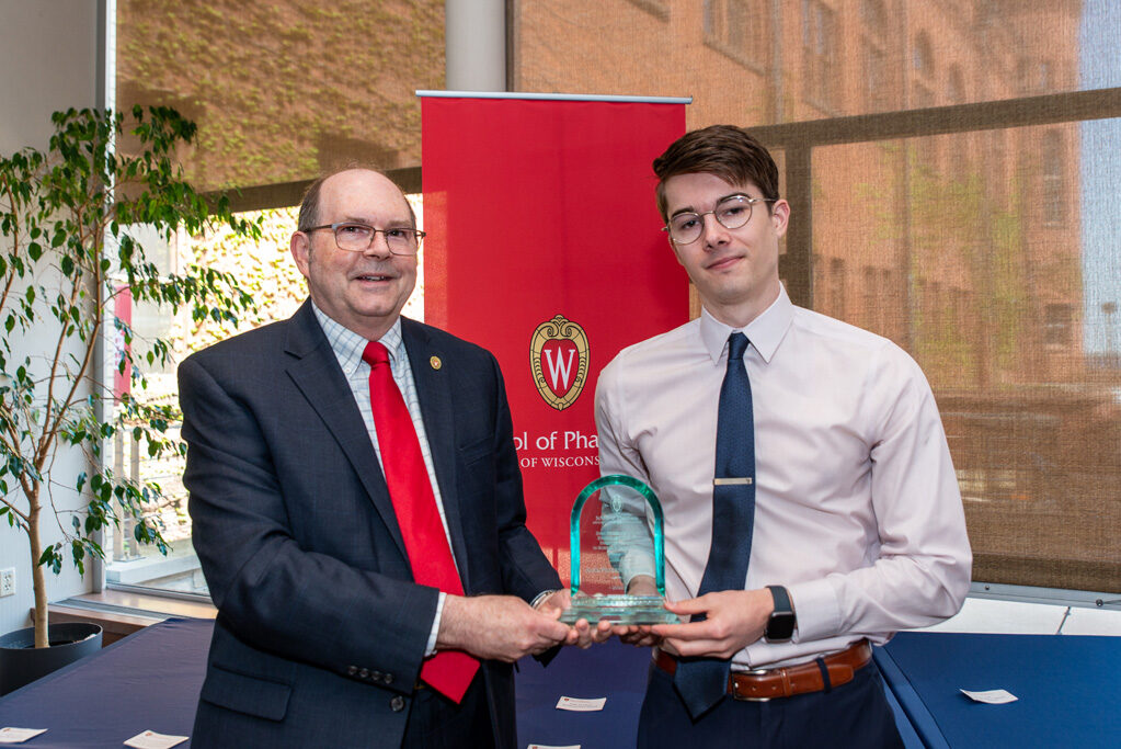 Faculty member and UW Pharm award recipient holding his award
