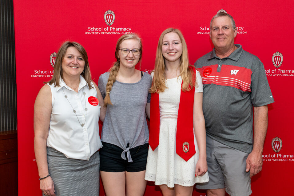 PharmTox student with family in front of red backdrop