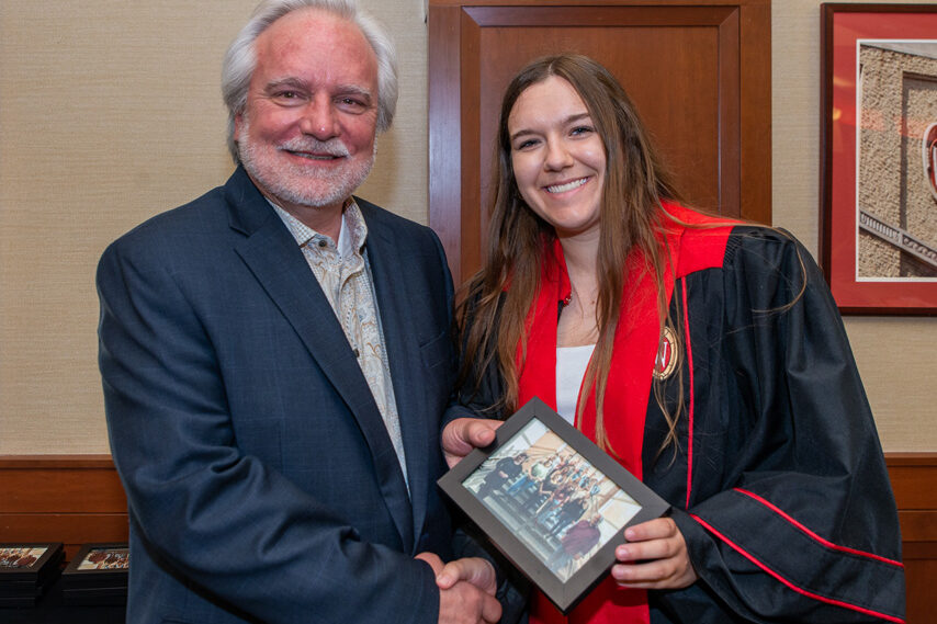 Graduate student holding a picture frame with prof. Jeffrey Johnson