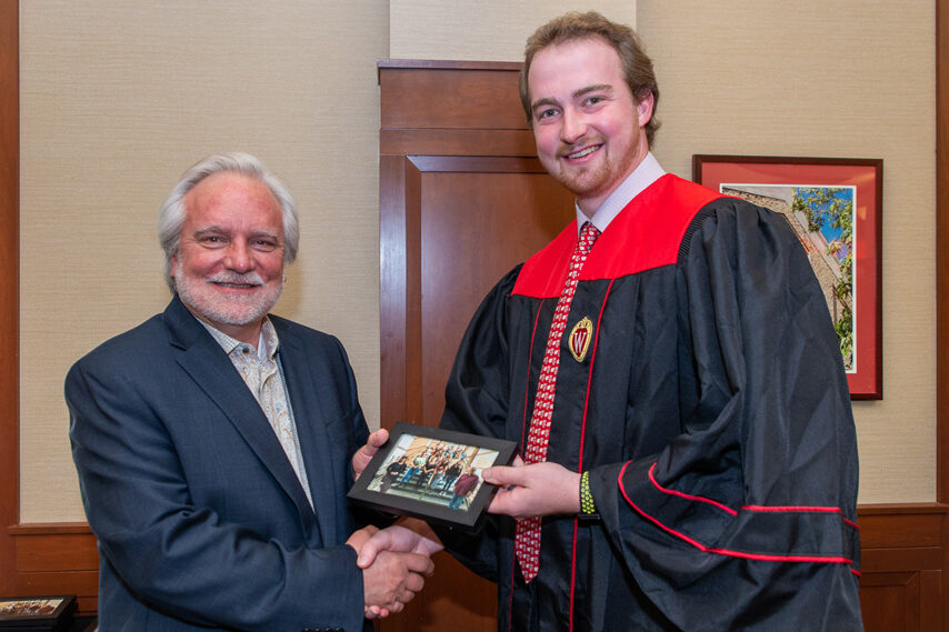 Graduate student holding a picture frame with prof. Jeffrey Johnson