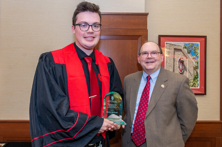 graduate student holding an award with a faculty member