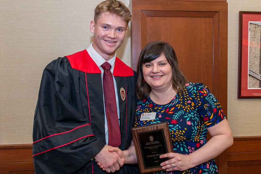 graduate student with faculty member holding an award