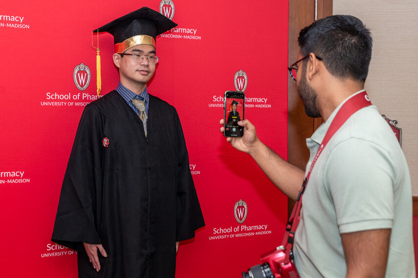 Graduated student in front of red backdrop