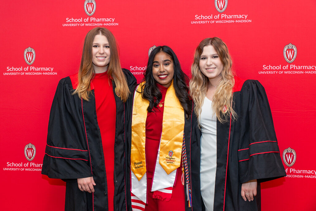 Graduated Pharm students in front of red backdrop