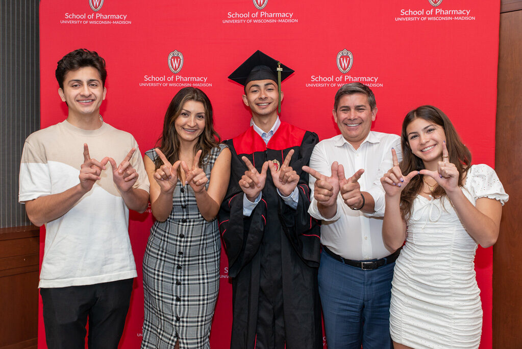 Graduate student with their family forming a W with their hands