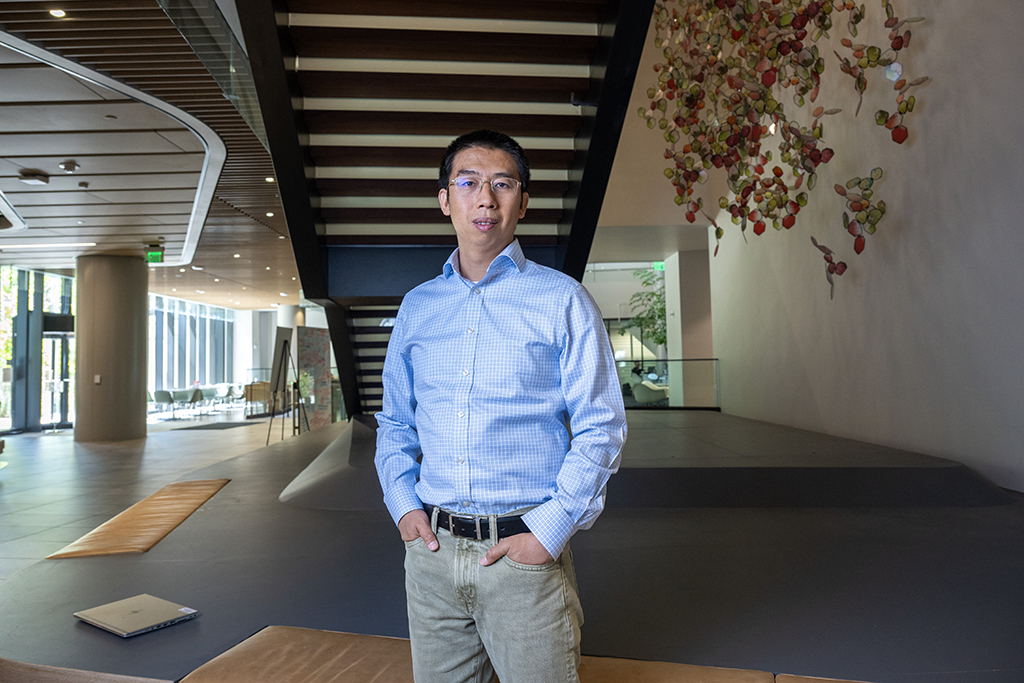 Wei Zhang poses under a stairway, smiling