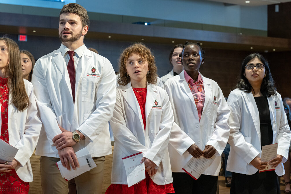 PharmD students stand and sing in their white coats