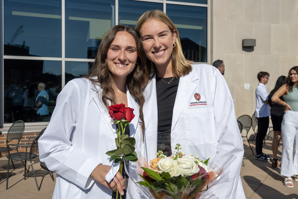 PharmD students pose in their white coats with roses