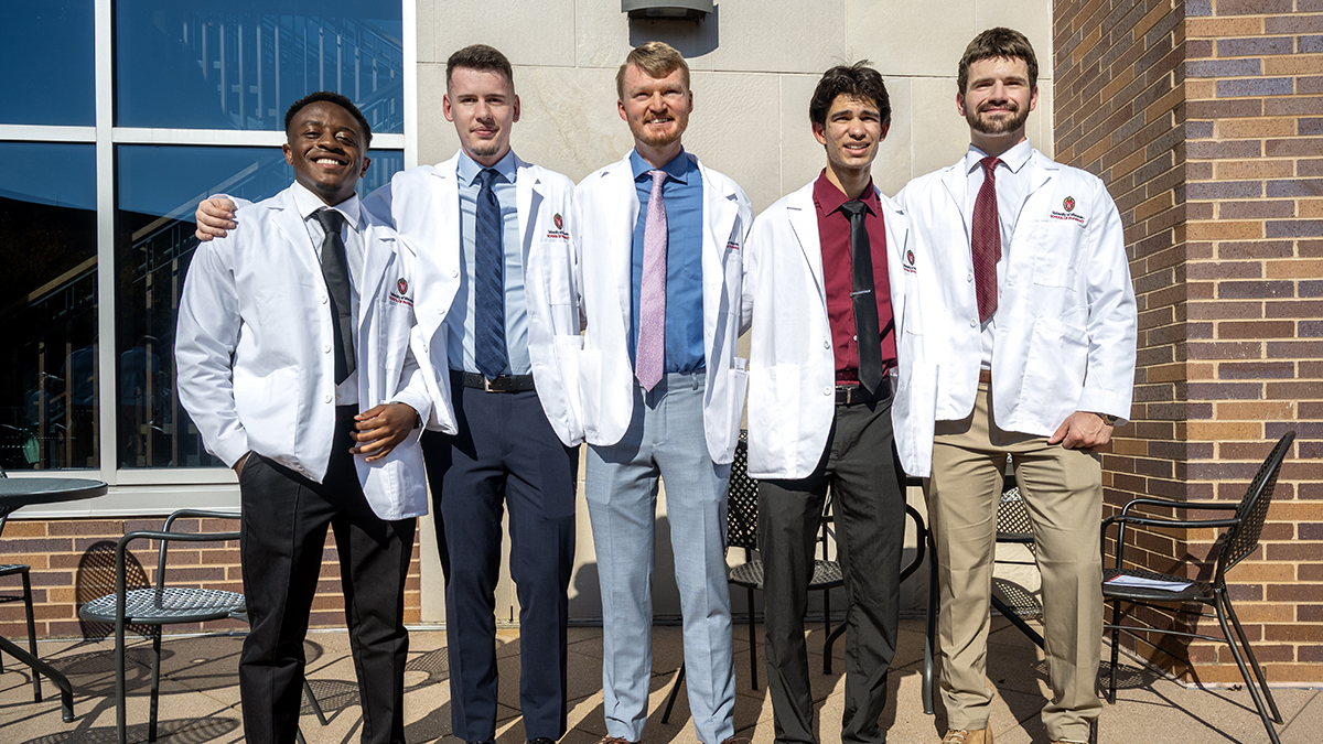 Emmanuel Khan Sama, Fransi Killo, Tyson Elliott, Dillion Francis, and Nicholas Albers pose in their white coats