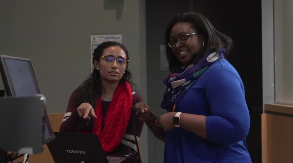 A student and Olayinka Shiyanbola speaking together during a class