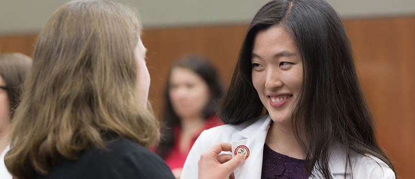 A third-year PharmD student smiles as she receives her pin