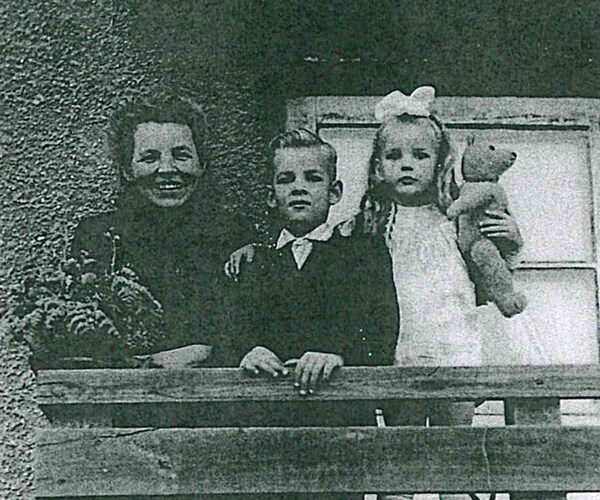 Black and white photo of Anna Apinis with her son and daughter at a railing