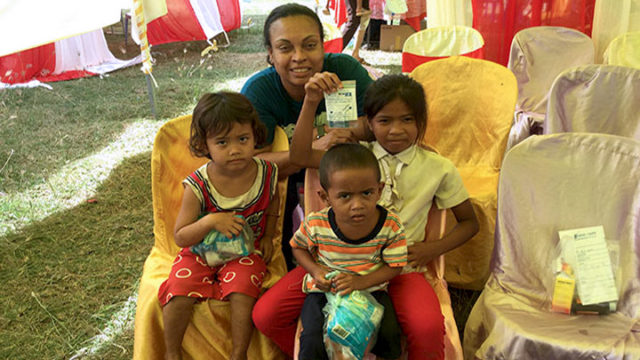 Eva Vivian poses with 3 small children during a healthcare mission to Cambodia