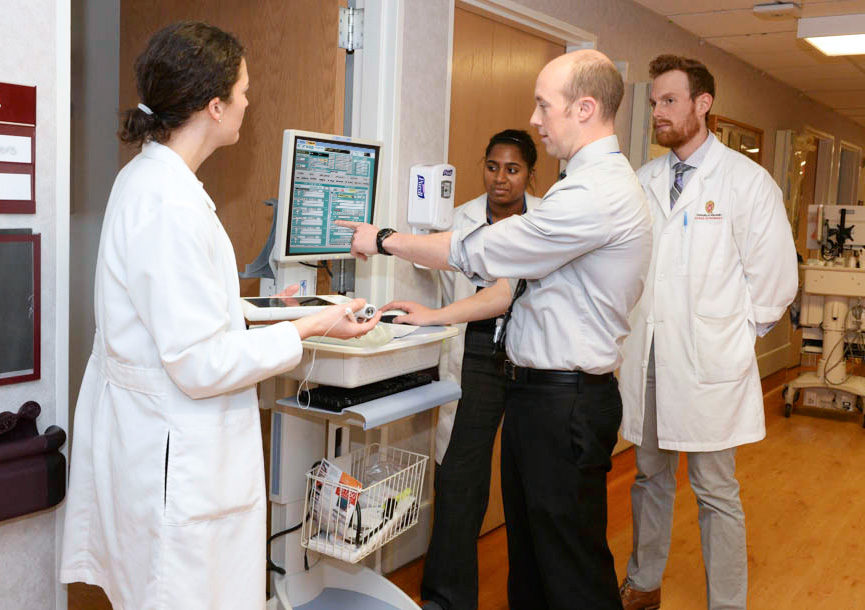 Pharmacists convene around a computer.