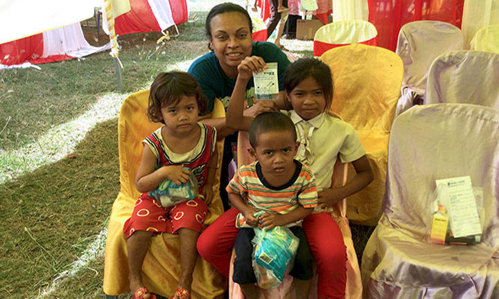 Eva Vivian poses with 3 small children during a healthcare mission to Cambodia