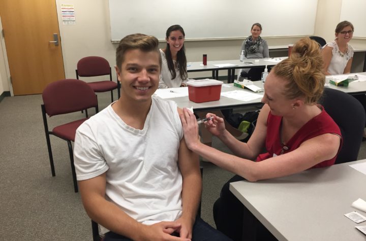 Andrew Vandermause receiving flu shot from Taylor Kitzke