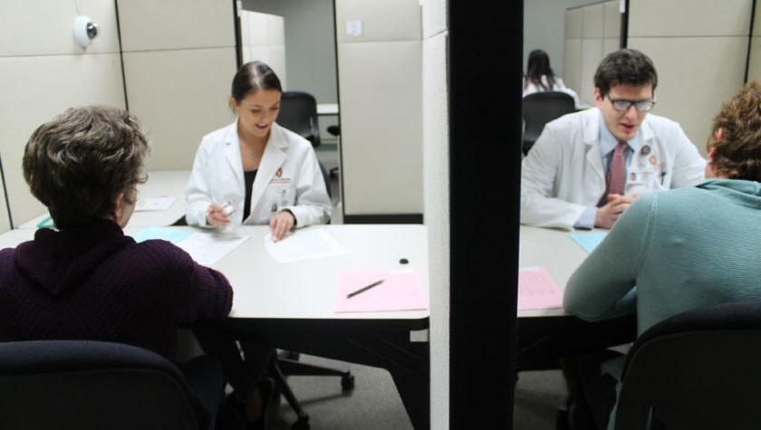 communications lab with students wearing white coats speaking to patients