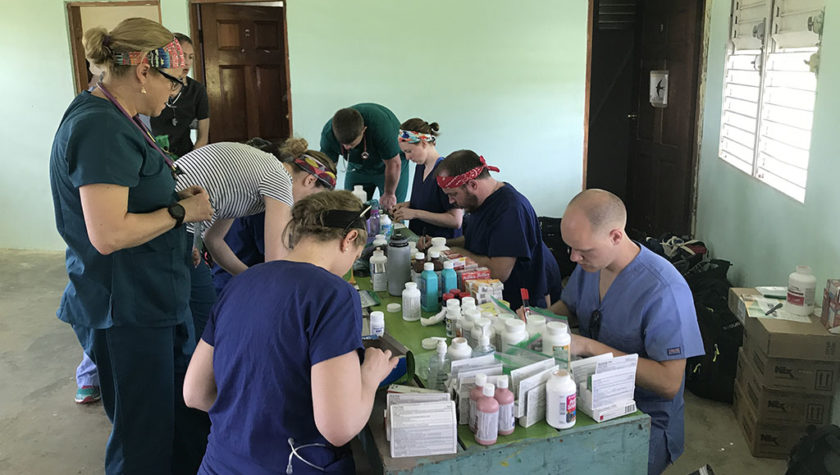 Alex Wontor with other students and pharmacists at table filled with supplies