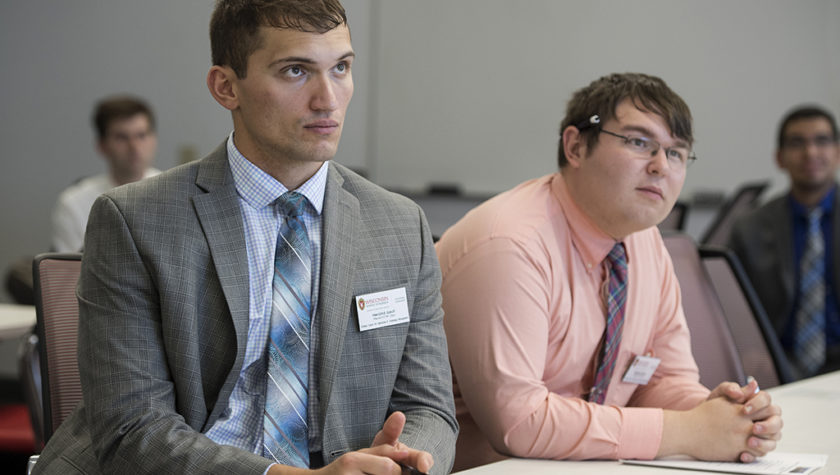 Herolind Jusufi and Michael Heltne sitting at a table watching the speaker