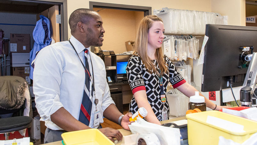 Hussain Harun and Abigail Moore working at station in pharmacy