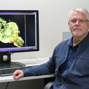 Michael Taylor at his desk with 3D rendered image on computer