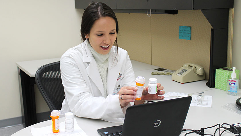 Taylor Hauser holding prescription bottles up to a webcam.