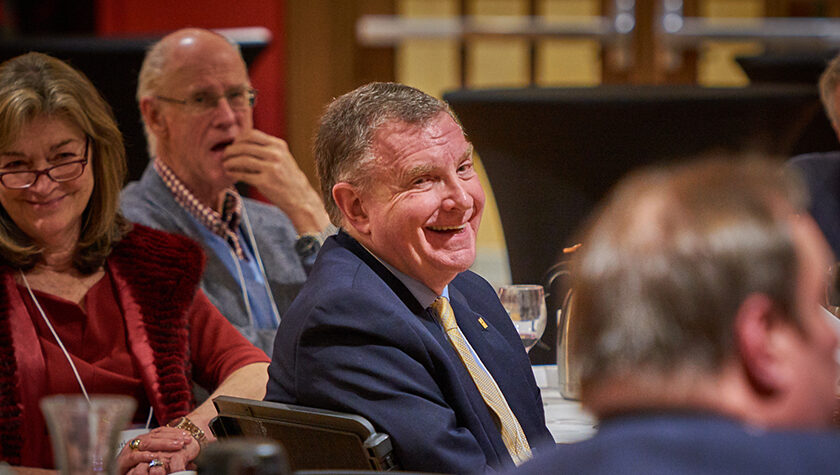 Russ Jensen smiling at the table in an event hall