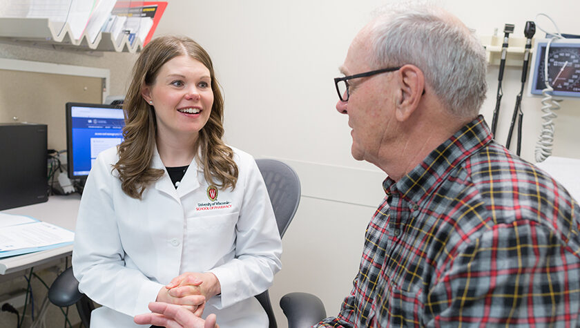 Andrea Porter in a white coat, with a patient.