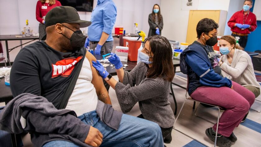 PharmD students Janvi Shah (left) and Kathryn Freitag (right) give the COVID-19 vaccine to a couple at the vaccine clinic held at the McKenzie Family Boys & Girls Club in Sun Prairie. Photo by Paul L. Newby II