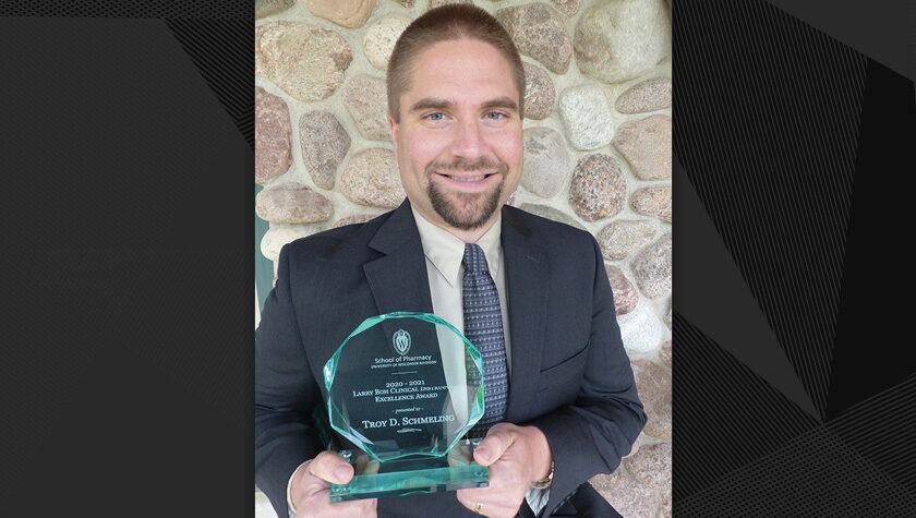 Troy Schmeling holding his glass excellence award