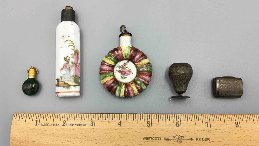 Old perfume bottles compared against ruler