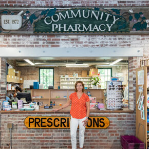 Aimee Speers poses in front of the Community Pharmacy sign