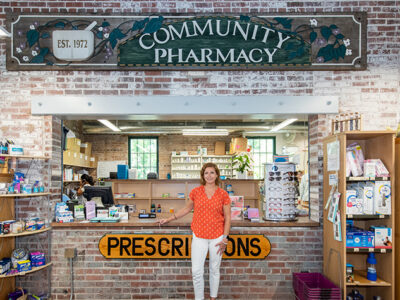 Aimee Speers poses in front of the Community Pharmacy sign