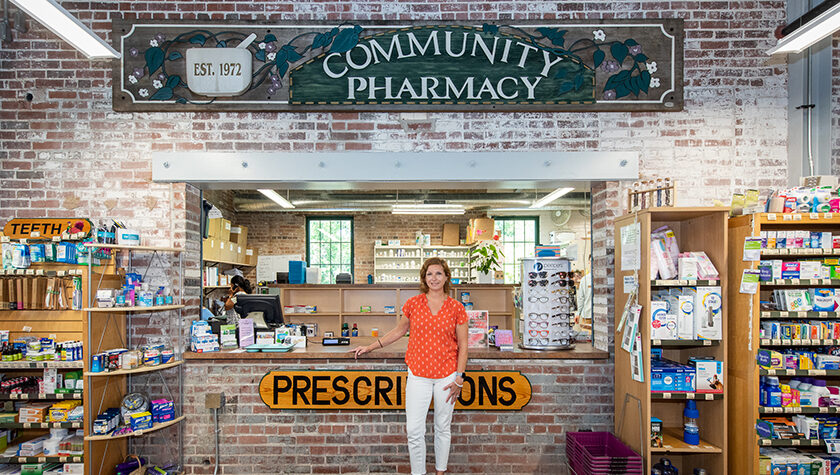 Aimee Speers poses in front of the Community Pharmacy sign