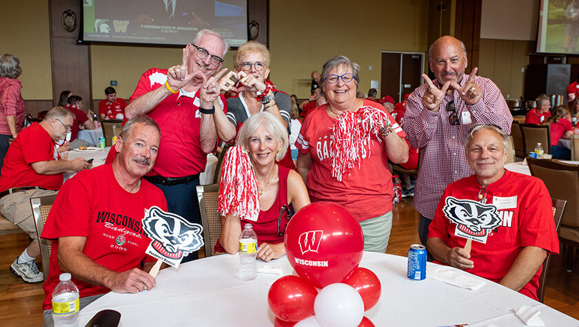 A group of alumni smile and pose with Badger gear.