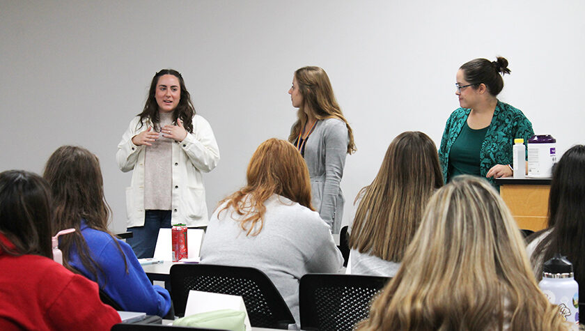 Courtney Quinn, Emma Dreischmeier, and Amanda Margolis speak in front of a class.