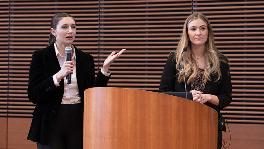 Alexis Doering and Elle Noone speaking at a podium