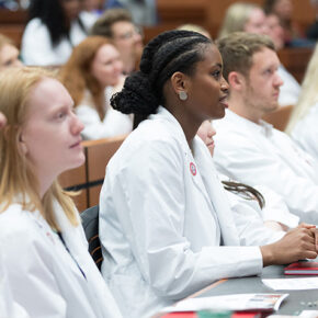 PharmD students in white coats sitting in a row