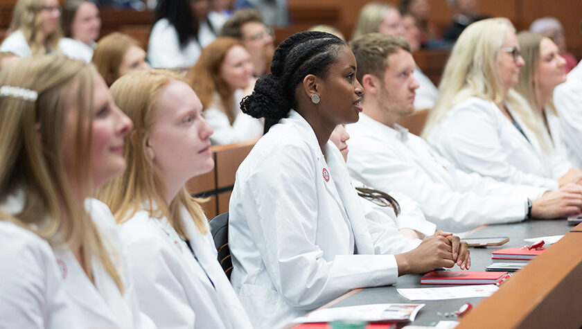 PharmD students in white coats sitting in a row