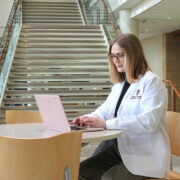 Morgan Oettinger, in her white coat, works at her computer.