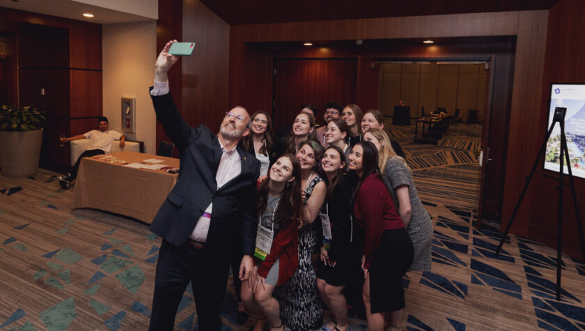 Advancement Dean Dave Mott takes a photo with a group of student alumni attendees of the APhA 2024 Alumni and Friends Reception.