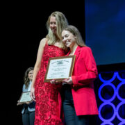 Lauren Glaza holding the award next to a woman in a red dress