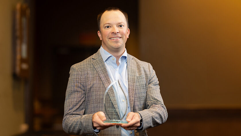 Jason Bergsbaken holds his Young Alumnus of the Year award