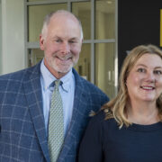 Lee Vermeulen and Jill Kolesar pose for a photo in front of a building