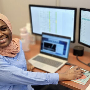 Fatima Abdul Rasheed at a desk working with computers and smiling