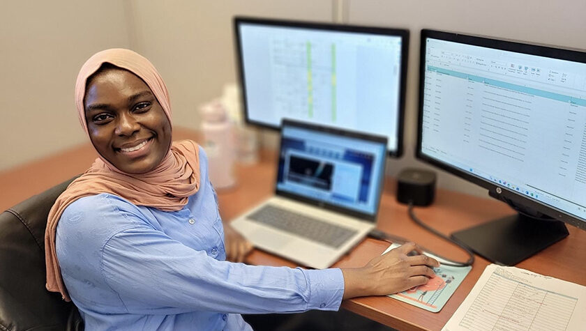 Fatima Abdul Rasheed at a desk working with computers and smiling