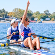 Sophia Vitas in a scull boat waving to shore wearing Team USA clothes.